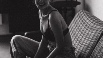 Smiling Young Woman in Bra and Jeans Sitting on the Couch