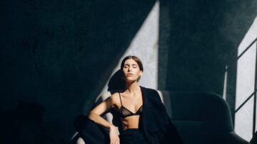 Model in Black Chiffon Bra and Pants Sitting on the Sofa with a Blazer Draped over Her Shoulder