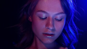 Thoughtful female in bra with glowing face and closed eyes