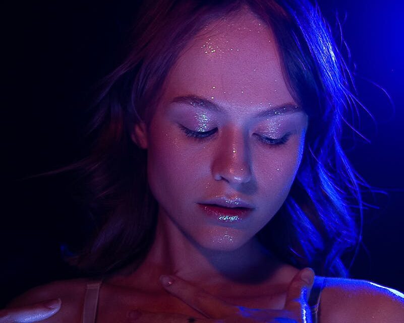 Thoughtful female in bra with glowing face and closed eyes